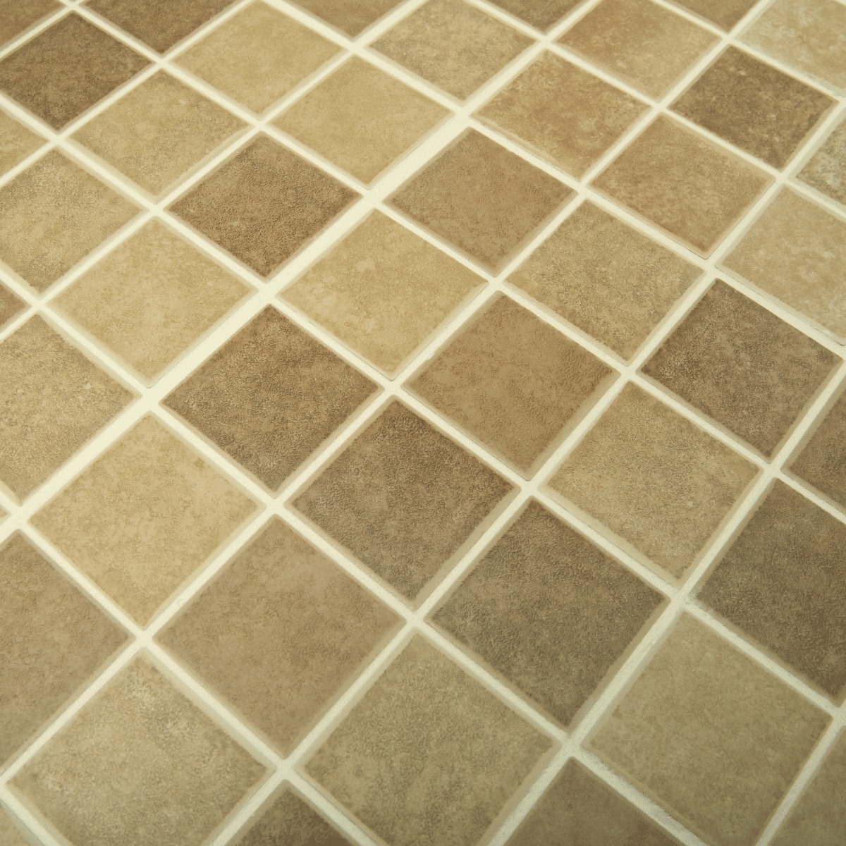 Close-up of a tiled surface with square tiles in various shades of beige and brown, arranged in a grid pattern with light-colored grout lines between each tile.